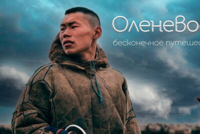 Young reindeer herder in traditional fur parka beneath a dramatic cloudy sky, nomadismi myos