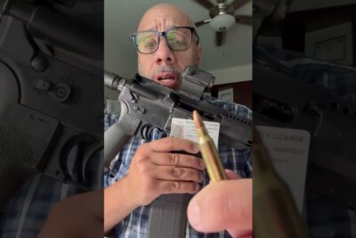 Man holding an AR-style rifle and a cartridge close to the camera in an ockupation ar demonstration.