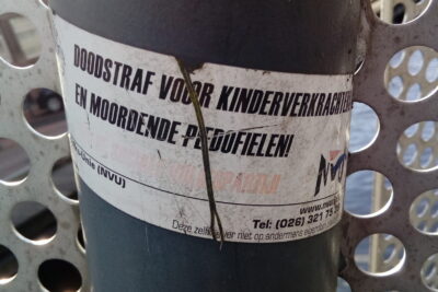 Weathered sticker on a pole demanding om dodsstraf for child rapists and murderous pedophiles