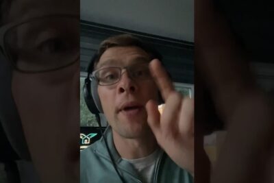 Close-up of a man wearing headphones and glasses speaking and pointing at the camera on tarkeaa 131