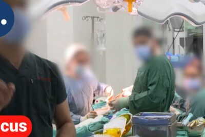 Surgical team in an operating room performing a cosmetic procedure with masked staff and surgical lights, operaciones esteticas 1.