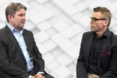 Two professionals in business attire engage in a seated discussion illustrating oppiminen voi and collaborative learning.