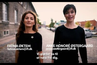 Two female colleagues walking side by side on a cobblestone street pa arbejdspladsen.