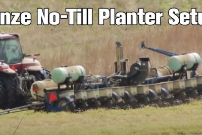 Tractor pulling a large no-till multi-row planter across a grassy field, pa planeter 1
