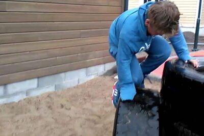 Child climbing on a large black tire at a sandy schoolyard pa skolen