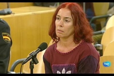 Red-haired woman seated at a courtroom microphone during parot doctrine proceedings