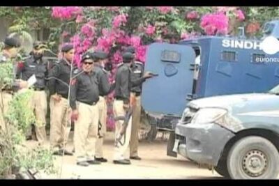 Uniformed police officers and armored vehicle at a security scene with flowering shrubs, peine mort 3