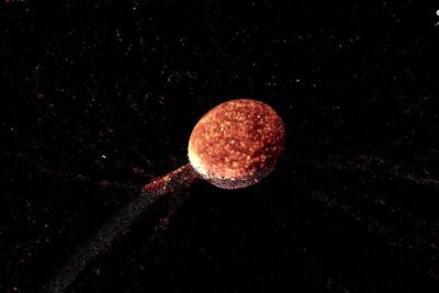 A glowing reddish pianeta nano with a textured surface and a trailing stream of particles against a dark starfield.