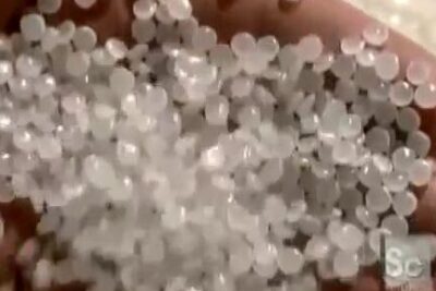 Hand holding translucent white polymer pellets, plastic bags 2