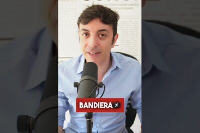 Person speaking into a studio microphone with a visible red BANDIERA banner, porre propria 1.
