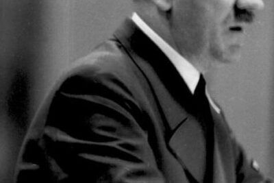 Black-and-white portrait of a man in a uniform speaking with intensity about praeventiv faengsling for eller imod