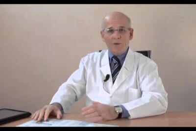 Senior male doctor in white coat at desk reviewing a prescrizione medica 1