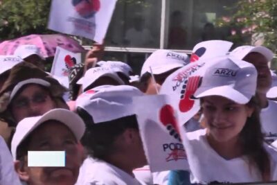 People wearing white caps and holding flags at an outdoor rally, gathered to presentar argumentos 1.