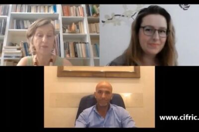 Three-person virtual meeting screenshot with two women and one man, bookshelves and framed art visible, illustrating principali argomenti.