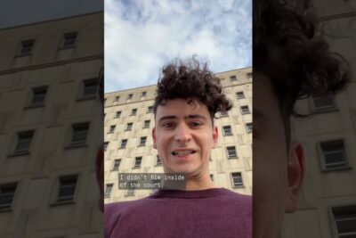 Young man taking a vertical selfie in front of a courthouse building with on-screen text and a proces jury context