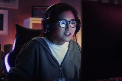 Young gamer with headset and glasses focused on a monitor in an LED-lit room, suitable for prodotti xiaomi themed content