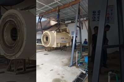 Large rotating industrial drum suspended by a hoist in a workshop used in prosessi eliot operations