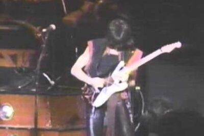 Guitarist performing a dynamic solo under stage lights at a ratt liv show.