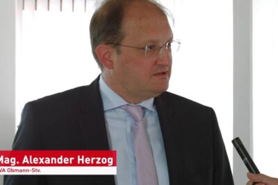 Business professional in suit being interviewed with a microphone, illustrating recht selbstbestimmung