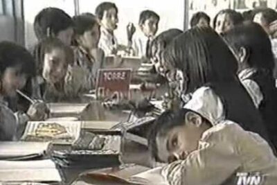 Group of schoolchildren seated at shared desks in a busy classroom illustrating reforma educacional 2
