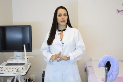 Fertility specialist standing beside an ultrasound machine and exam table prepared for reproducao assistida 1.