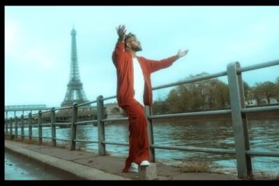 Person in red outfit posing by the Seine with the Eiffel Tower in the background, reseaux sociaux 15.
