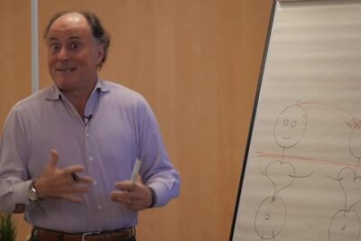 Presenter demonstrating a flipchart diagram to resoudre conflits with arrows and heart symbols