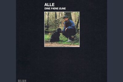 A man crouching beside a black dog on a wooded trail suggesting rette vej.