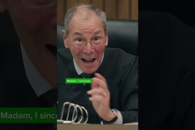 Presiding judge in a black robe speaking energetically at a courtroom bench, rettssaker jury