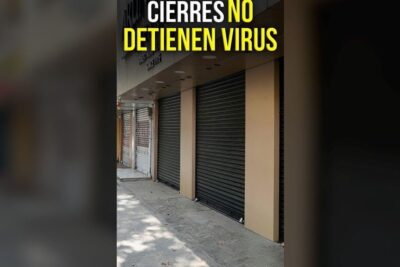 Row of closed metal roll-up shutters on storefronts depicting revoca mandato and business closures