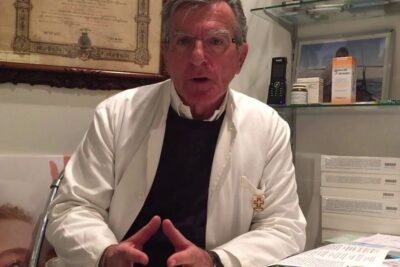 Medical professional in a white coat gesturing during a consultation about rimedi omeopatici 1 in an office