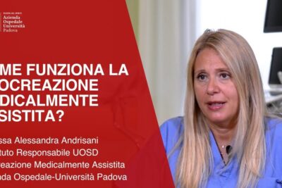 Medical clinician beside a red informational panel about riproduzione assistita 1 in a hospital setting.