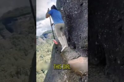 Person balancing on a narrow cliff ledge while holding a pole, demonstrating risken for 2