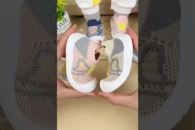 Pair of flexible pastel knit infant sneakers being bent to show soft white sole, sapatos bebes 2