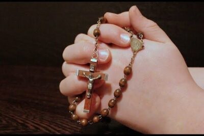 Hand holding wooden rosary with metal crucifix, scienziati sostengono