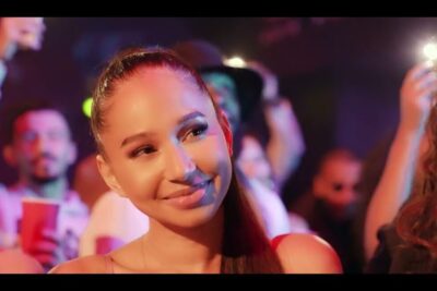 Smiling woman in a colorful nightclub crowd se pa.