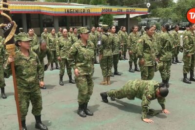 Uniformed soldiers in formation with one recruit doing push-ups during servicio militar 2 training.