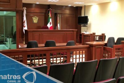 Empty wood-paneled courtroom with judge's bench and visitor seating, sistema justicia 1