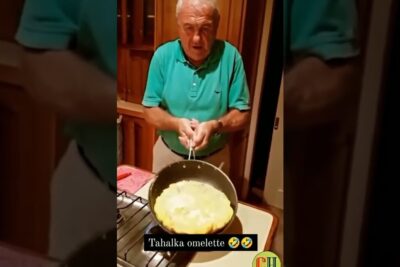 Elderly man flipping a large omelette in a skillet on a home stove, slumpen ar casual cooking scene.