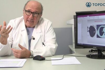 Senior physician at desk reviewing lung CT images while advising on ways to smettere fumare.