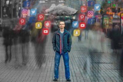 A man stands alone in a crowded, blurred street beneath a cloud of floating social icons representing social media 20.