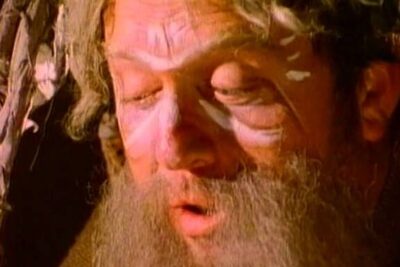 Bearded actor in theatrical makeup portraying a philosopher in a socrates trial reenactment.