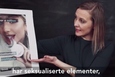 A woman points to a printed social media ad mockup featuring a teeth-whitening device and smiling model, sosiale medier 15