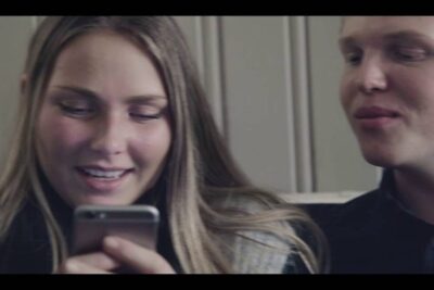 Two people sitting close and viewing a smartphone screen together highlighting social interaction on sosiale medier 9.