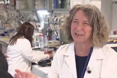 Smiling female scientist in a busy research laboratory with colleagues and equipment, sperimentazione animale 1.
