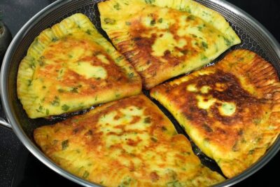 Skillet with four golden-brown pan-fried cheese and herb pastries ready to serve spise kod
