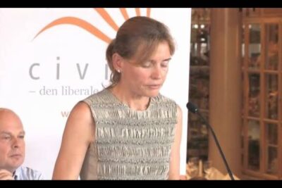 Woman speaking at a lectern during a conference event related to statens rolle 1