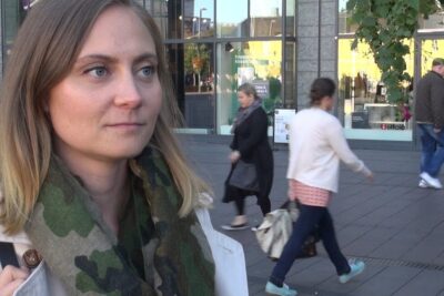 Close-up street portrait of a woman wearing a camouflage scarf in an urban shopping area, suitable for sukupuolineutraali avioliitto 1