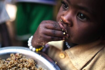 Young child eating a bowl of grains with visible focus on nutrition and sustainable development 1