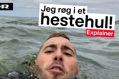 Swimmer partially submerged in choppy sea taking a close-up selfie while caught in a svomme strommen coastal current